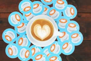 Coffee cup with heart latte art surrounded by stickers with heart latte art.