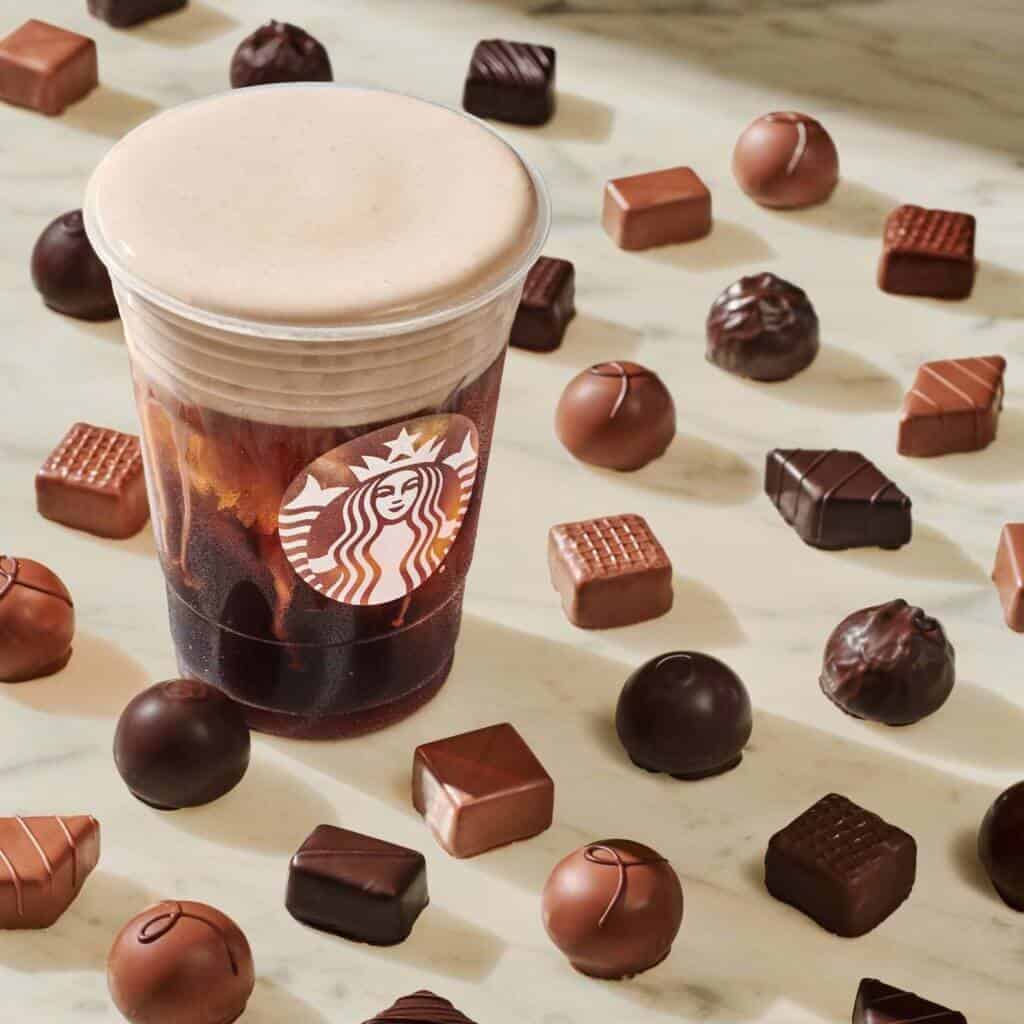 Starbucks chocolate cream cold brew on a counter with chocolate candies all around.