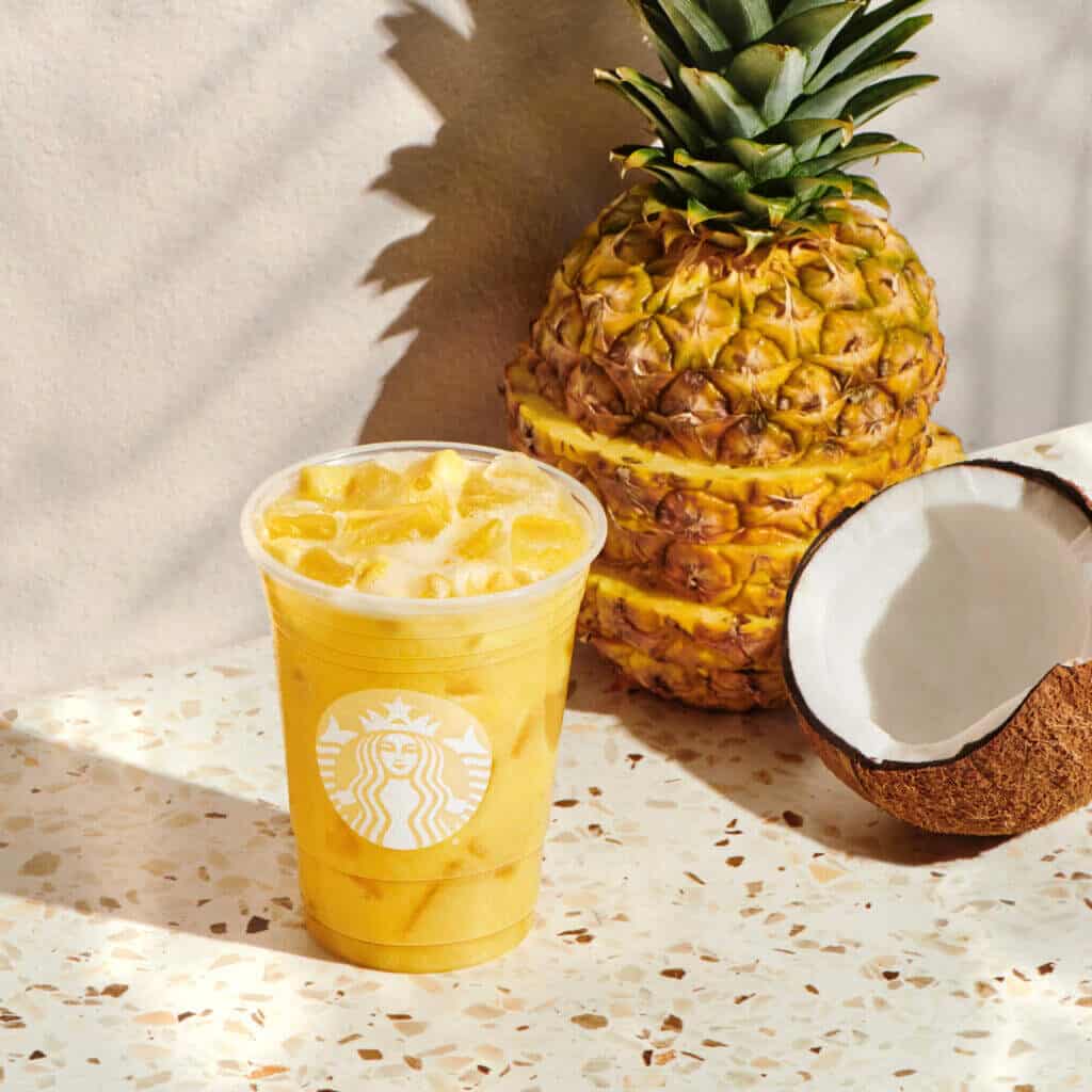 Starbucks paradise refresher drink with a coconut and pineapple in the background