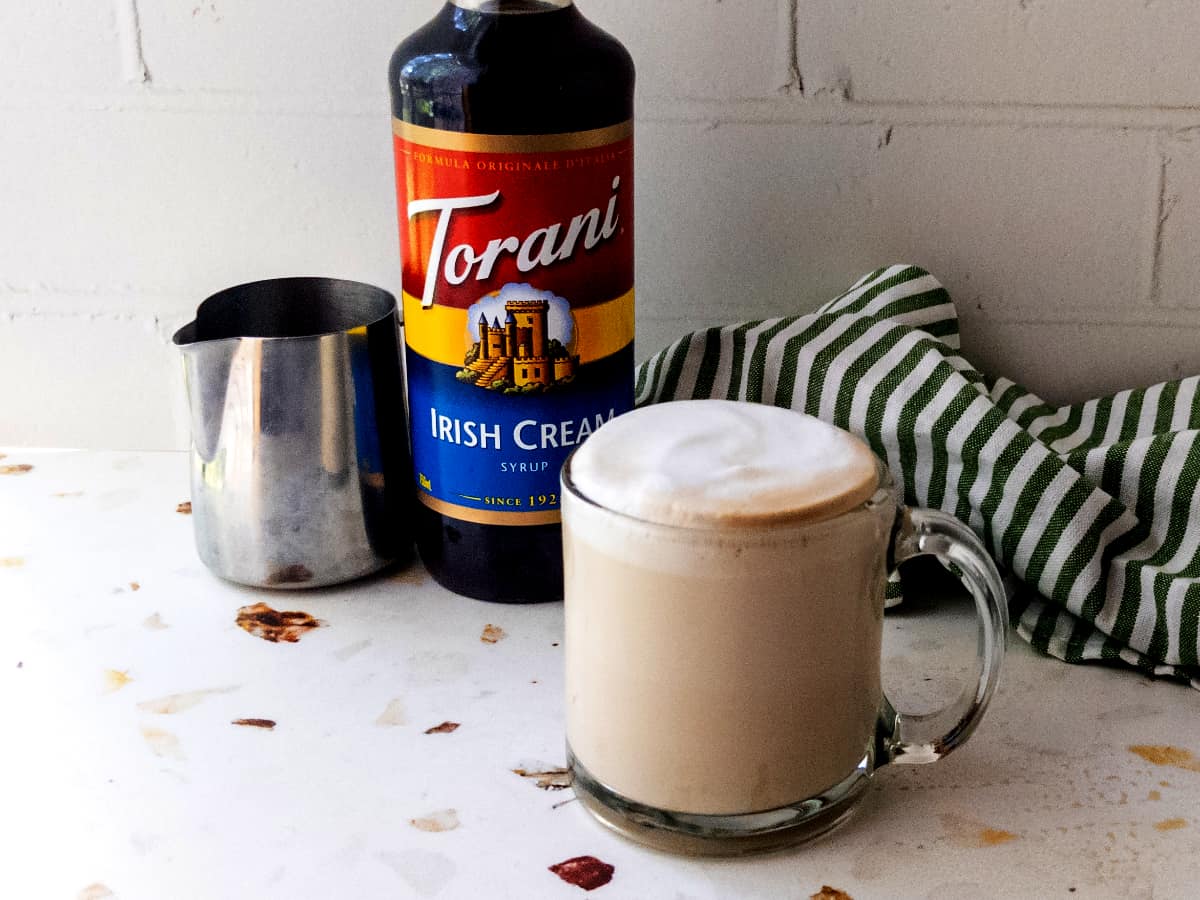 A hot Irish cream breve with a bottle of Torani Irish cream syrup in the background.